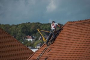 professional roofer on a red tile roof harnessed in and making repairs in destin, florida