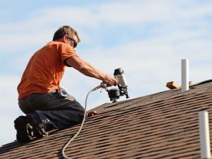 Professional roofer using a nail gun to install asphalt shingles during roof repair in Destin, FL — expert roof repair services by Destin Roofing Inc.